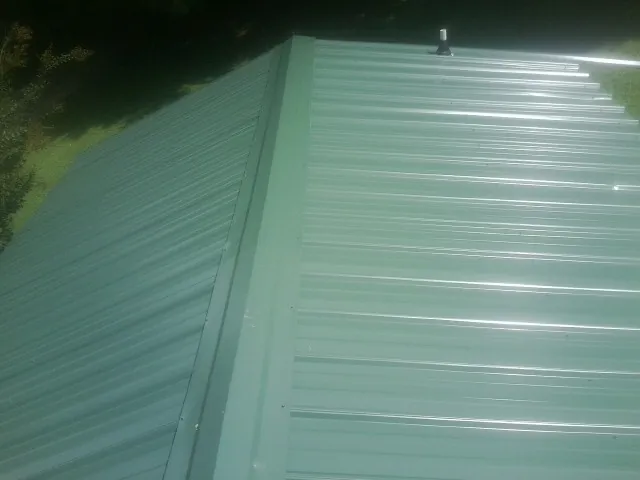 New green metal panels meeting at the ridge of a roof — Flat Roof Repair work by our crew in Glen Aubrey