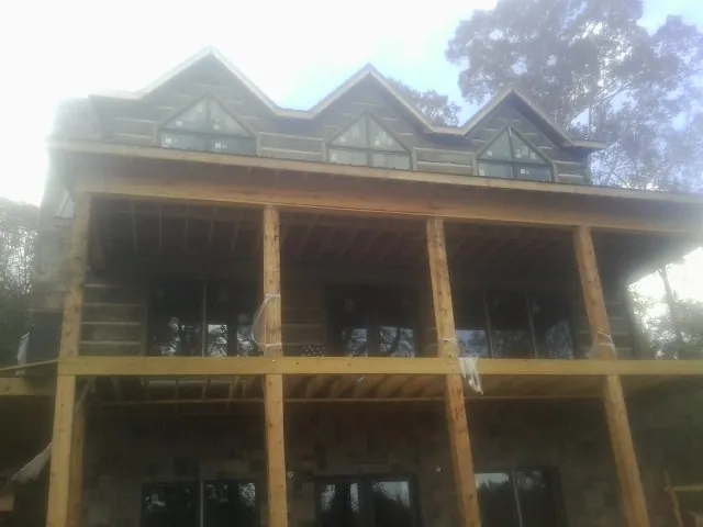 Dormers and porch framing on a large log home under construction — Roof Coating work by our crew in Glen Aubrey