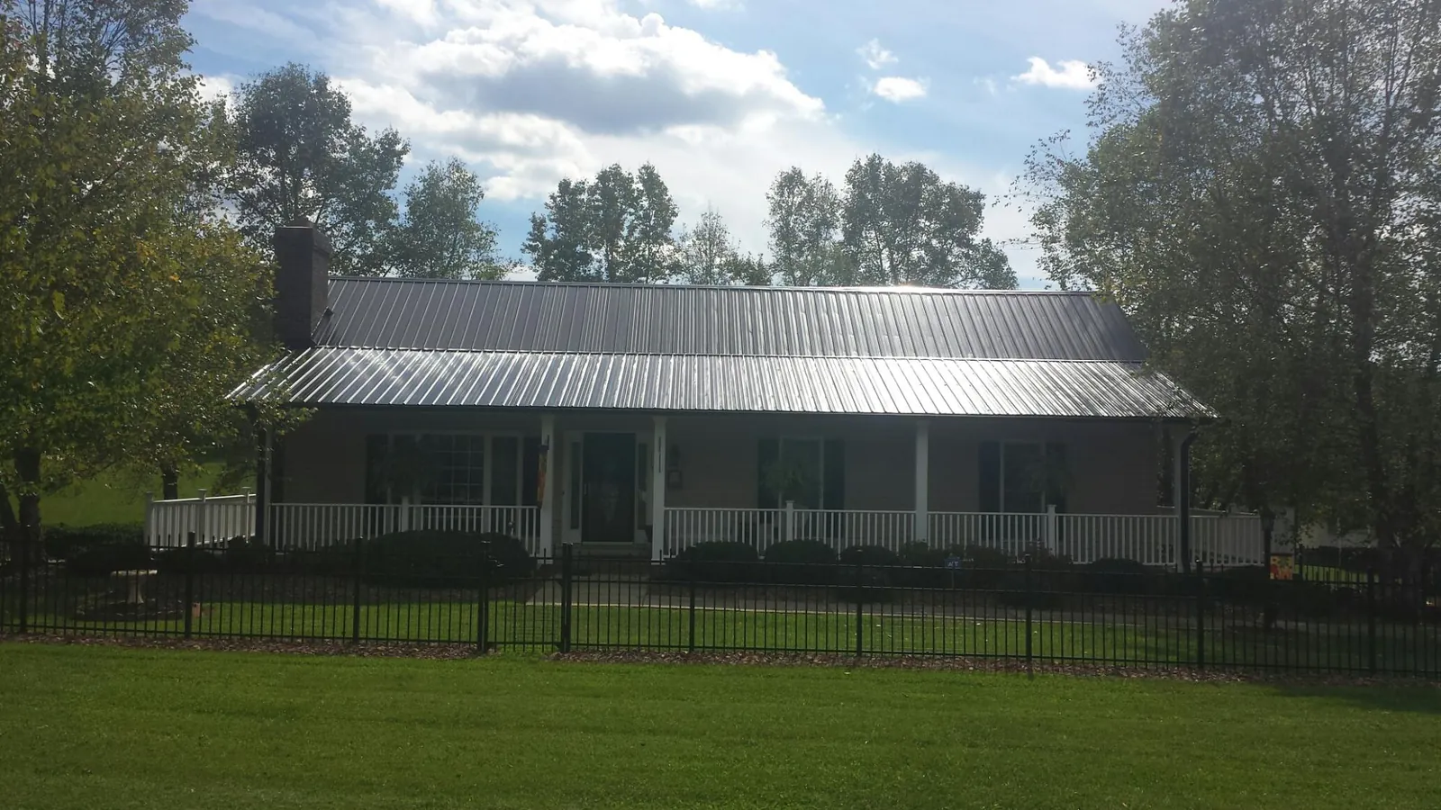 Gray metal roof on a brick ranch with a full width front porch — Gutter Guard Installation work by our crew in Glen Aubrey