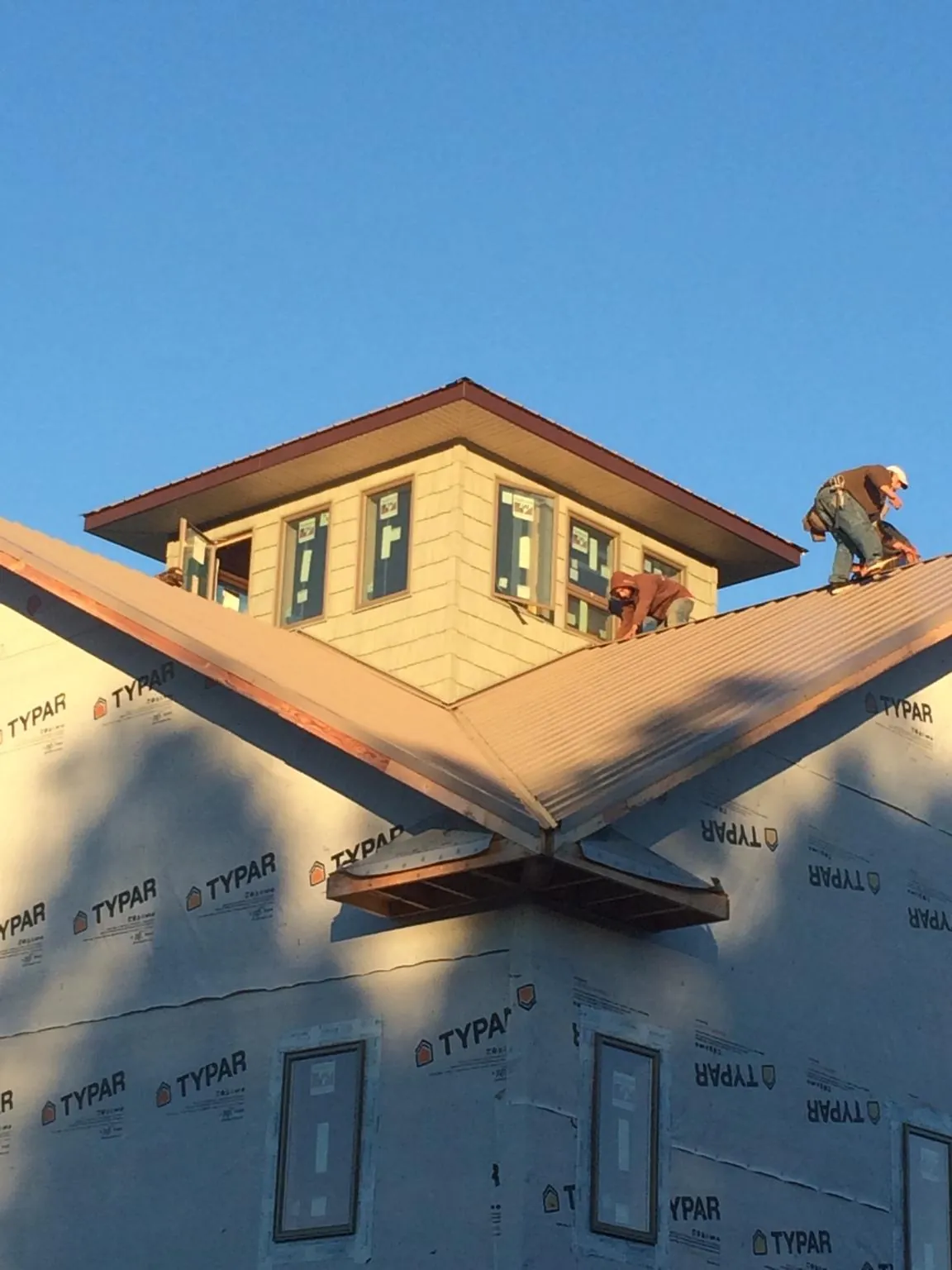 Roofers working around a rooftop cupola on a new metal roof at sunset — Roof Waterproofing in Glen Aubrey by Roofing Brothers